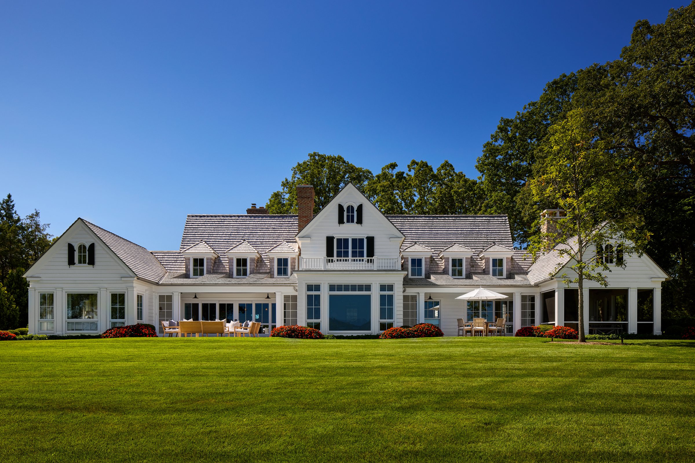 Waterfront shingle-style custom home at dusk, built by Mosher Dolan