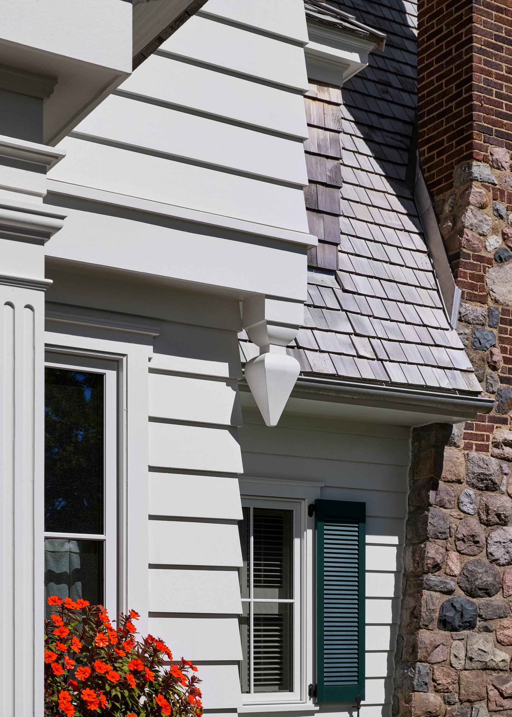 Painted shingle siding meeting a fieldstone chimney