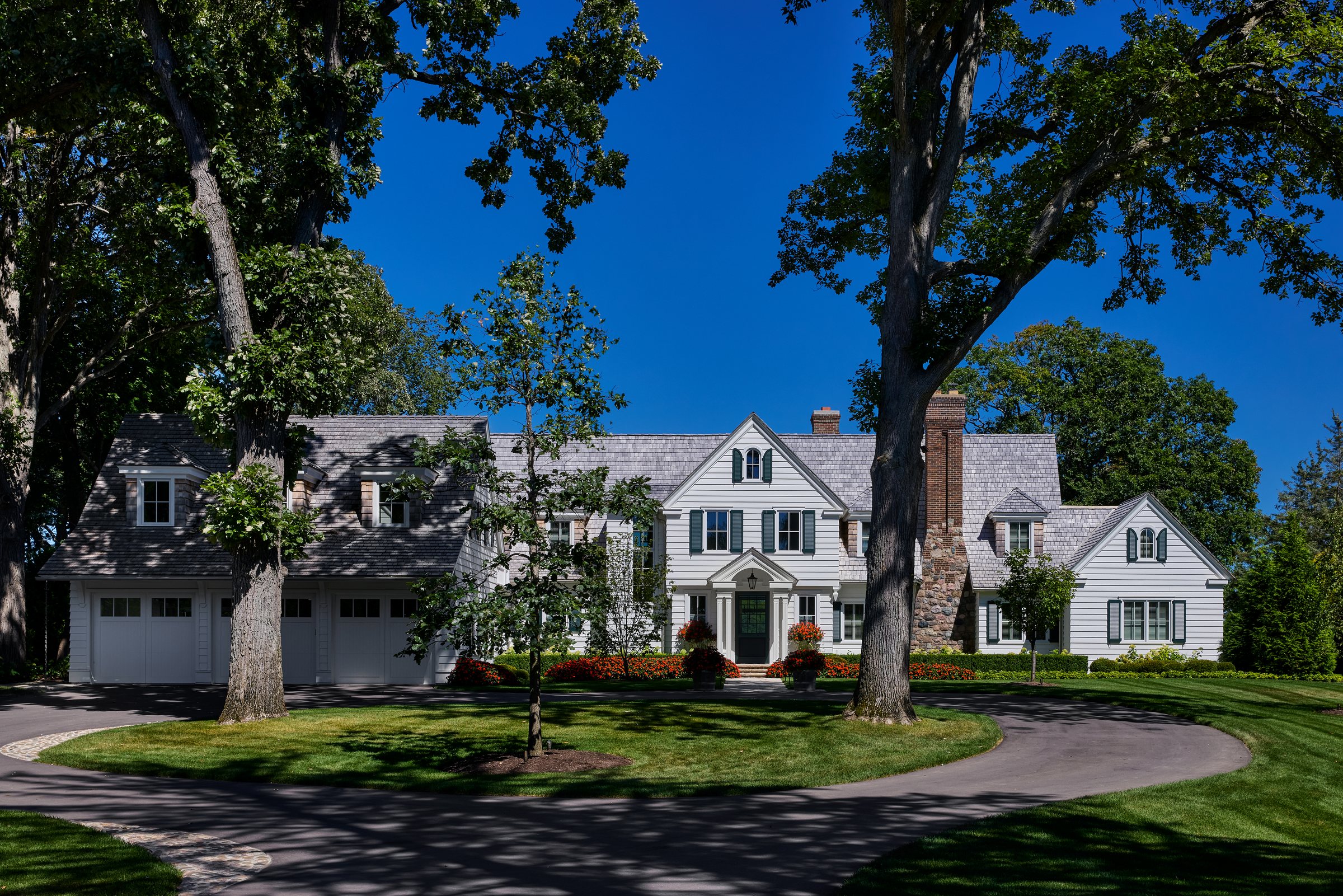 Shingle-style lakefront home from the drive, beneath a mature oak