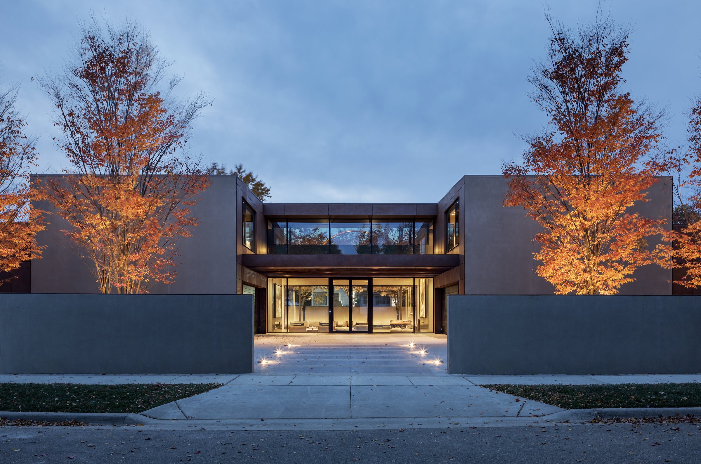 Modern home of dark volumes and glass among autumn trees in Birmingham