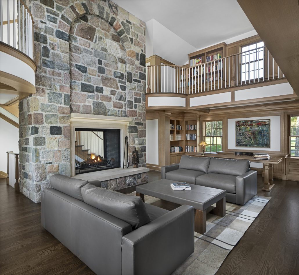 Two-story library with a stone fireplace and balcony